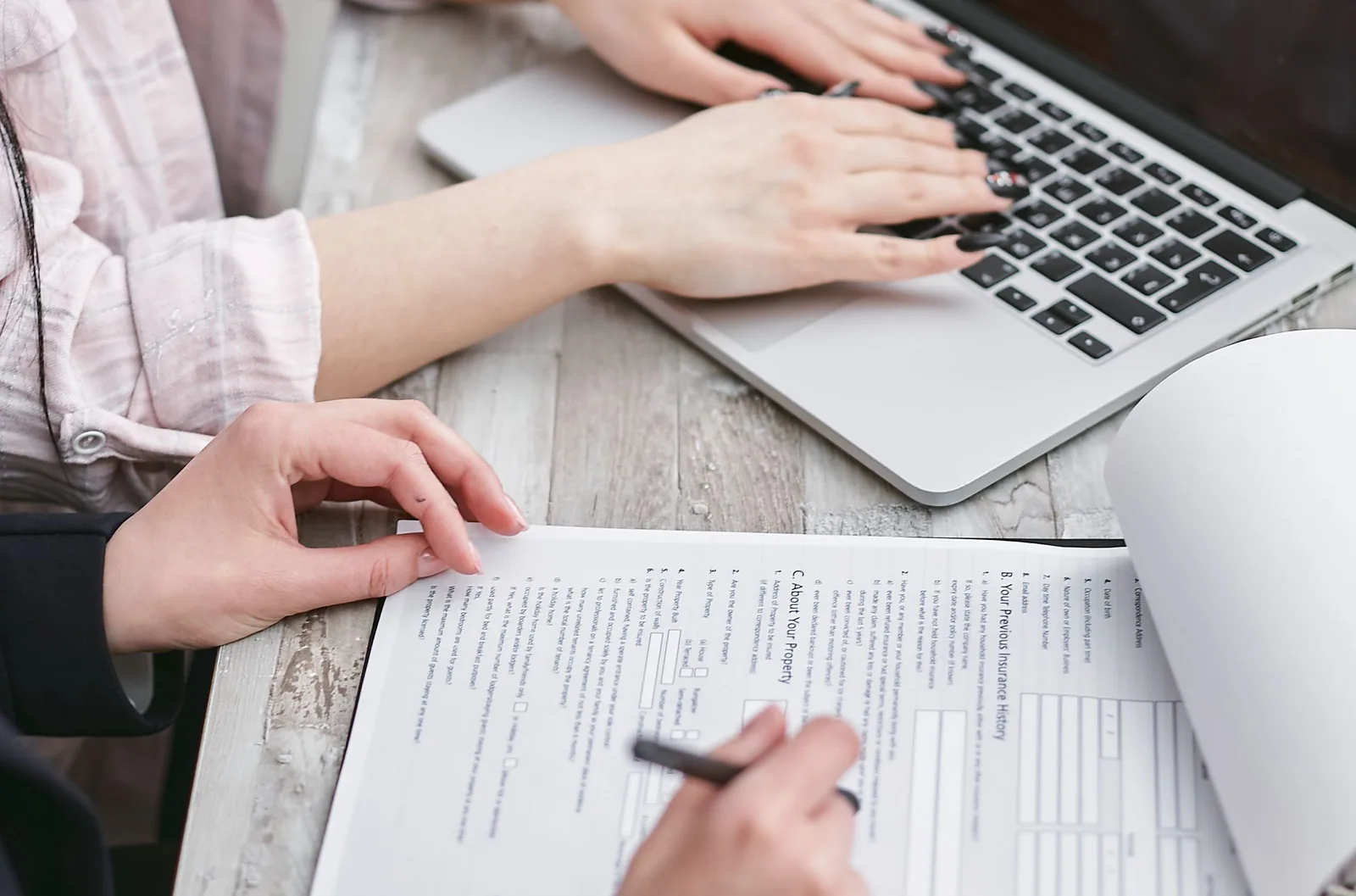 Close-up of hands typing on a laptop and reviewing business documents, focused on finance and legal tasks. How SBA loans fund marketplace startup revenue models in Texas